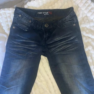 Mörkblå jeans från Pory Star - Snygga mörkblå jeans från Pory Star med slitningar och coola detaljer på fickorna. Jeansen har dekorativa knappar och broderi på bakfickan. Klassisk femficksmodell i stretchigt denimtyg som sitter skönt och passar till det mesta. Bootcut modell som är lågmidjade