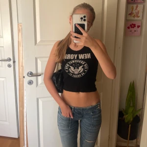 Svart croppad linne från brandy - Säljer ett svart croppat linne med breda axelband och tryck framtill med texten 'NEW YORK'. Toppen har en tight passform och är från brandy melville därav one size strl. Hör av dig vid frågor💕