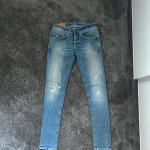 Dondup - Snygga ljusblå jeans från Dondup i modellen George. Jeansen har skinny passform, slitningar framtill och dragkedjor på bakfickorna. Klassisk femficksdesign och låg midja. Perfekta för dig som gillar en smal siluett och coola detaljer.
