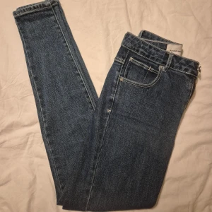 Blå skinny jeans från Abrand Jeans - Säljer ett par klassiska blå skinny jeans från Abrand Jeans. De har hög midja, fem fickor och dragkedja med knapp framtill. Jeansen är i ett mjukt denimtyg med snygga kontrastsömmar och en liten logga på bakfickan. Perfekta till sneakers eller boots.
