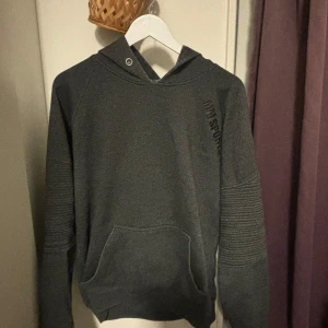 Mörkgrå hoodie från MM Sports XL - Mörkgrå hoodie från MM Sports i storlek XL. Tröjan har huva, ribbade detaljer på ärmarna och en stor magficka. Perfekt för chill dagar eller när du vill ha en sportig look. Mjuk insida och diskret logga på bröstet.