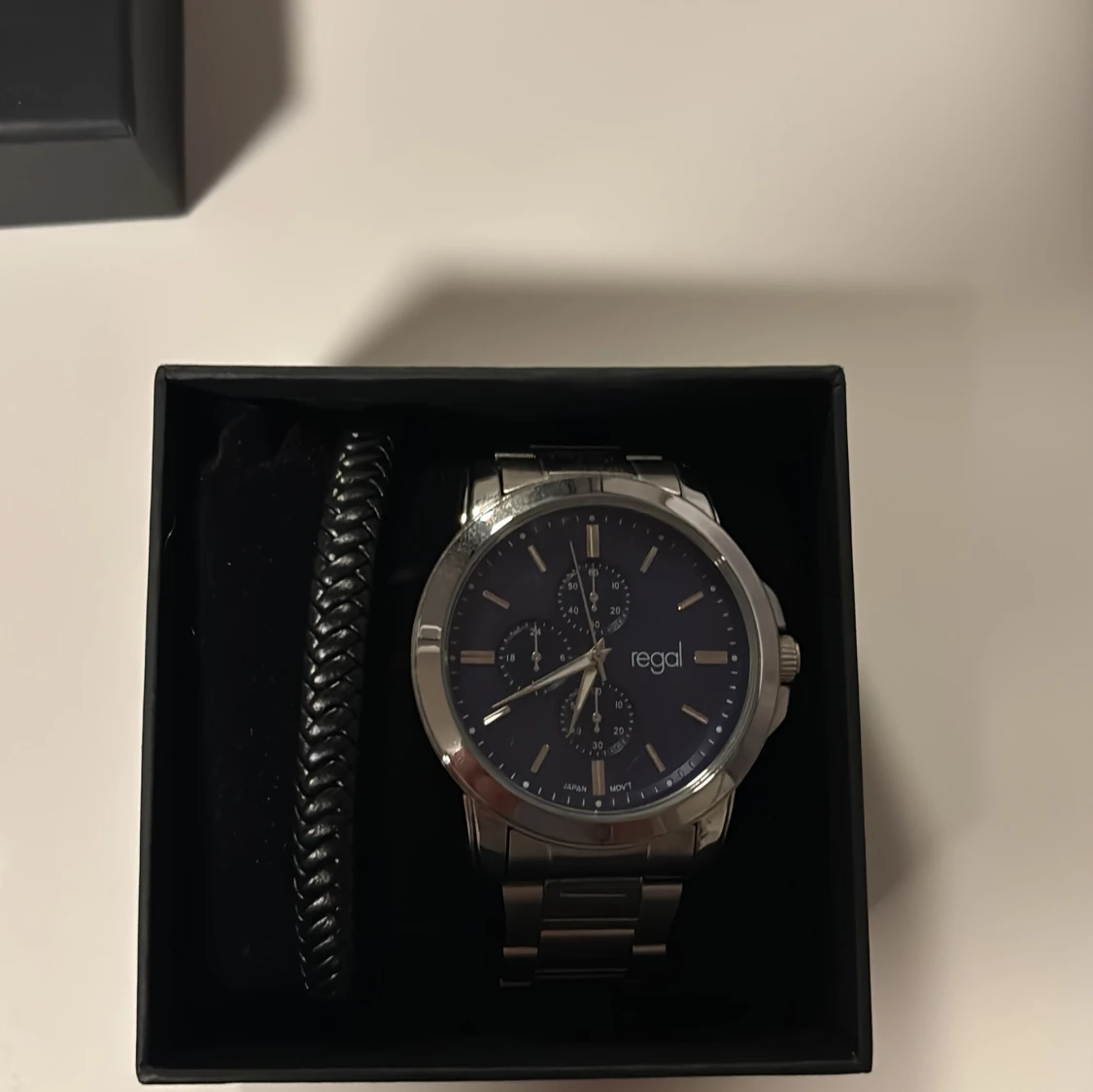 Regal klocka med blå urtavla och länk