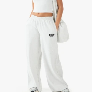 DSGN Studio gråa vida mjukisbyxor - Ljusgråa mjukisbyxor som är helt nya med prislappen kvar. Modellen heter DSGN Studio Broderade Ribba Midjebyxor och är i färgen Ash grey. Dom är vida i benen och är medelhög midja 💕