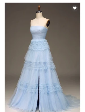 Balklänning -  Axelbandslös tyllklänning i ljusblått med glitter. Veckad topp och flera lager tyg i kjolen. Silverglitter. Stängs med dragkedja i ryggen. Endast använd vid ett tillfälle. Den är LÅNG! Jag borde lagt upp den men istället är det smutsig i nederkant, se bilder, i övrigt i princip i nyskick. Tänker en kan lägga upp den så det smutsiga försvinner. Storlek saknas men uppskattas passa ca XS (34/36) Mått bröst mätt armhåla till armhåla rakt över ca 40 cm Mått kjollängd mätt från mi