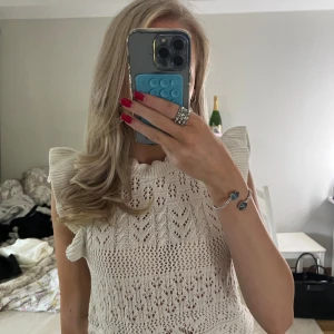 Vit stickad blus från ONLY Studio - Säljer en söt vit stickad blus från ONLY Studio i storlek XS. Toppen har volangdetaljer vid axlarna och halsen samt ett snyggt hålmönster över hela tröjan.💗