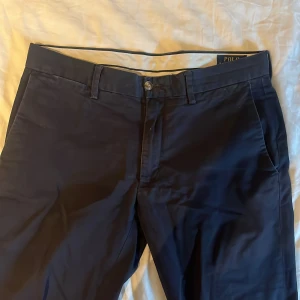 Mörkblå chinos från Polo Ralph Lauren - Snygga mörkblå chinos från Polo Ralph Lauren i stretchigt bomullsmaterial. Byxorna har slim fit passform. W30/L34