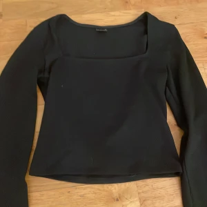 Svart långärmad topp med fyrkantig ringning - Snygg svart topp med lång ärm och fyrkantig ringning. Storlek S