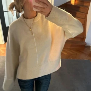 Beige stickad tröja från Zara - Supermjuk och oversized beige stickad tröja från Zara. Tröjan har rund halsringning, breda muddar och en snygg söm mitt fram. Perfekt för lager-på-lager och chill dagar. Passar dig som gillar en avslappnad och trendig stil.
