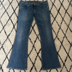 Blåa flared jeans från Big Star - Säljer ett par super söta blå bootcut jeans från Big Star, modell Extra Low Flair. Jeansen har super låg midja och är flared. Midjemåttet är ca 40 cm och innerbensmåttet är ca 78cm! Måttet vid gylfen är 20 cm. Super bra skick förutom längst ner på ena byxbenet där det är lite slitet!