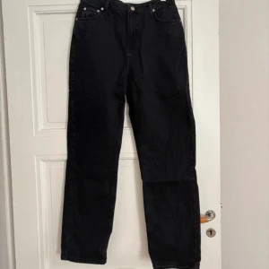 Svarta straight jeans NA-KD x Josefine HJ - Svarta jeans från NA-KD x Josefine HJ i rak modell med normal passform. Klassisk femficksdesign, hög midja och dragkedja med knapp. Tillverkade i denim av bomull. Perfekta för en clean och stilren look.