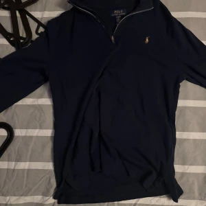 Marinblå half zip från Polo Ralph Lauren - Snygg marinblå långärmad tröja från Polo Ralph Lauren med klassisk broderad logga på bröstet. Tröjan har half zip-dragkedja och är gjord i mjuk bomull. Perfekt för en chill och stilren look.
