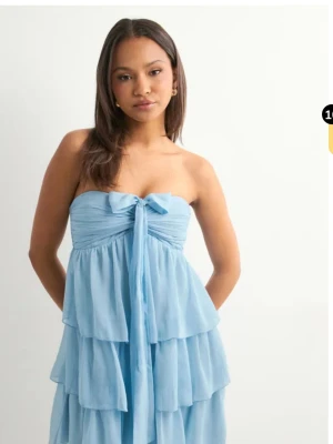 Ljusblå Balklänning  - Jag säljer den ljusblå klänningen från Nelly som är i samma längd som den rosa klänningen på bild 2.  Exakt vilken klänning jag säljer finns på bild 3-5. Klänningen finns inte längre tillgänglig att köpa på Nelly. Den går att knyta på flera olika och supersöta sätt. Den är använd en gång och jag absolut älskar den, men den kommer inte till användning. Inga defekter eller liknande. Jag är ungefär 170-175 cm lång, och den passade perfekt i längd på mig. Alltså: LJUSBLÅ, LÅNG BALKLÄNNING!!🤗