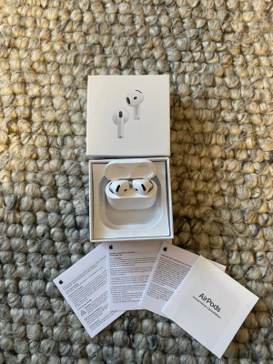 AirPods 4  - Snygga och moderna Apple AirPods 4. Komplett med förpackning och manualer. Hörlurarna och laddningsfodralet ser ut att vara i nyskick utan synligt slitage. Perfekt för trådlös musik med bra ljudkvalitet. Inte äkta 