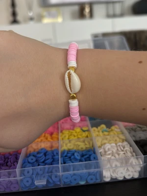 Fint sommar armband - Bilderna visar ett armband med rosa och vita pärlor samt ett snäckskal, väldigt fin att ha på semester eller sommaren.egen gjord