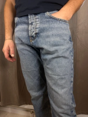 Levi's 501 ljusblå jeans straight fit - Klassiska Levi's 501 jeans i ljusblå tvätt med rak passform och knappgylf. Jeansen har fem fickor och tydliga kontrastsömmar. Perfekta för dig som gillar en tidlös och avslappnad look. Tillverkade i slitstarkt bomullsjeansmaterial.