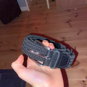 Svart flätat bälte från Jack & Jones - Säljer ett svart flätat bälte från Jack & Jones i storlek 80 cm. Bältet har snygga detaljer i skinn och ett klassiskt metallspänne. Perfekt accessoar för att lyfta din outfit med en stilren touch.