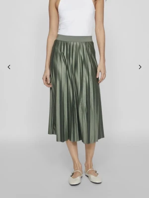 Räfflad grön långkjol från Vila - Snygg räfflad midikjol/ långkjol från Vila i en mjuk grön nyans, inte den nyansen på första bilden utan på de två senaste! Kjolen har ett brett resårband i midjan och ett glansigt, flowy tyg som ger en riktigt fräsch look.