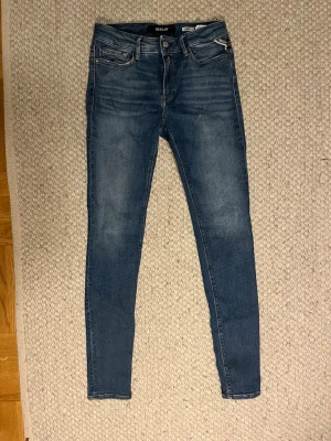 Blå slim jeans från Replay - Säljer ett par blå skinny jeans från Replay, modell Luzien. Jeansen har klassisk femficksdesign, smal passform. Snygga slitningar framtill och bakfickor med diskret broderi. Nypris 1100 pris 249 storlek 27-30