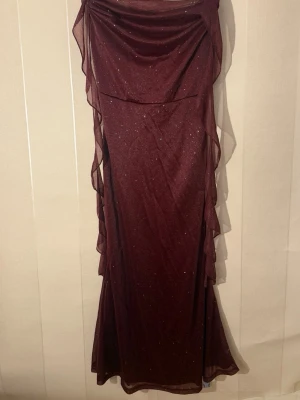 Fin Vinröd festklänning  - Supersnygg vinröd långklänning från Cider med glittrigt tyg och volangdetaljer längs sidorna. Helt ny och oanvänd med lappar kvar. Nypris: 398kr