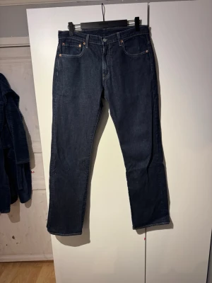 Levi's 569 mörkblå jeans straight fit - Säljer ett par klassiska Levi's 569 jeans i mörkblå tvätt. De har rak passform men lite baggy, fem fickor och silverfärgade nitar. Jeansen är tillverkade i robust denim och har den ikoniska läderlappen bak i midjan. Perfekta för dig som gillar tidlös stil och vill ha ett par riktigt schyssta jeans. W32 L34 