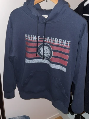 Saint Laurent Hoodie - Tjena! Säljer denna extremt feta och populära Saint Laurent hoodien! Den är bara använd en gång och den är iprincip i nyskick. Tröjan är i storlek M men kan möjligtvis även passa S. Hör av dig vid frågor eller funderingar ✅🔹