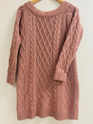 Rosa stickad tröja från NA-KD - Mysig rosa stickad tröja från NA-KD med flätstickat mönster och rund hals. Tröjan har lång ärm och ribbade muddar vid ärmslut och nederkant. Perfekt för kyliga dagar och enkel att styla med jeans eller kjol.