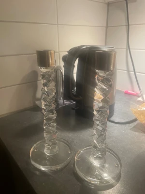 Orrefors ljustackar silver  - Bilden visar inga västar utan två ljusstakar i glas/metall. Ladda gärna upp en bild på en väst för att få en beskrivning.