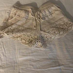Beige virkade shorts med snörning - Säljer ett par beige virkade shorts med snygg snörning i midjan. De har ett detaljerat spetsmönster och elastisk midja för skön passform. Perfekta för varma dagar och ger en chill vibe till din outfit. Dem är svin sköna så ja brukade även ha dem till myskvällar❤️  Säljer då jag inte har användning för dem längre❤️ Säljer för 100 pris kan diskuteras