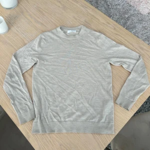 Beige stickad tröja från Selected Homme - Snygg beige stickad tröja från Selected Homme med rund halsringning och långa ärmar. Perfekt för lager-på-lager och enkel att matcha med jeans eller chinos. Stilren och tidlös design som funkar året runt.