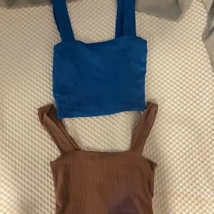 Två ribbade crop tops från Amisu XS - Säljer två ribbade crop tops från Amisu i storlek XS. Ena toppen är klarblå och den andra är brun, båda med breda axelband och fyrkantig halsringning. Perfekta för sommaren och lätta att matcha med jeans eller kjol.