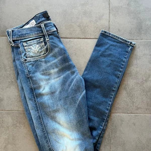 Replay Anbass blå jeans herr - Säljer ett par Replay Anbass jeans i klassisk blå tvätt med snygga slitningar och kontrastsömmar. Modellen har raka ben och fem fickor, samt Replay-logga på bakfickan. Perfekta för dig som gillar en tidlös jeanslook.