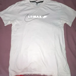 Vit Nike Air Max t-shirt i bomull - Vit t-shirt från Nike med Air Max-tryck och klassisk swoosh-logga på bröstet. T-shirten har rund halsringning och korta ärmar. Tillverkad i mjuk bomull för en skön känsla. Perfekt för dig som gillar sportig och clean streetstyle.
