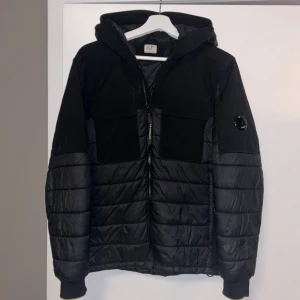 Svart pufferjacka från C.P. Company - Svart pufferjacka från C.P. Jackan är i relativt bra skick och perfekt för kyligare dagar. Storleken är 14 men sitter som xs. Plasten på ärmen är något skrapad (se bild 5).