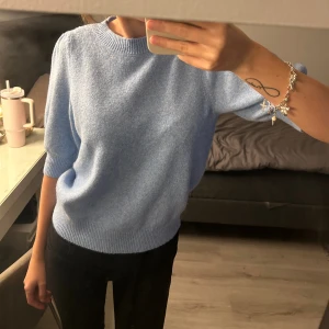 Ljusblå stickad tröja från Vero Moda - Superfin ljusblå stickad tröja från Vero Moda med rund halsringning och halvlånga puffärmar. Tröjan har ribbade muddar vid ärmslut och nederkant, vilket ger en snygg och bekväm look. Perfekt för dig som vill lägga till lite färg i garderoben!