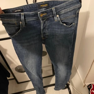 Blå slim jeans Jack & Jones - Slim fit jeans från Jack & Jones i klassisk blå tvätt. Modellen heter Slim/Glenn och har smal passform med normal midja. Nu tar jag över vad ai skrev då dom ör stretchiga och sitter skönt har ett till par som är mörk blå och snygga kan skicka bilder på dom det ör storlek 30-32 så passar dig som väger 60kg-68kg och ör runt 160 och  175 bra skicka inga skador 300kr för ett par och båda för 550 skriv om du vill se dom andra lika dana samma model bara mörkare blå Med vänlig hälsning, kungen med k 