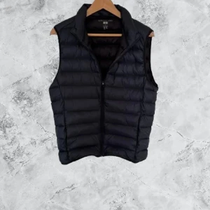 Svart dunväst från Uniqlo, storlek S - Svart, lätt och vattenavvisande dunväst från Uniqlo i storlek S. Västen har quiltad design, hög krage och dragkedja framtill. Perfekt för lager-på-lager och enkel att bära med sig tack vare sin ultralätta känsla.