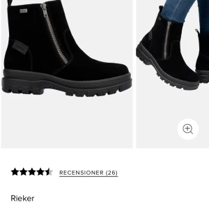 Svarta boots från Rieker, storlek 36 - Svarta boots från Rieker med grov platt sula och rund tå. Snygg mocka på ovansidan och praktisk dragkedja på sidan för enkel på- och avtagning. Perfekt för dig som gillar stilrena och robusta skor med coola detaljer.