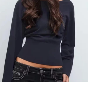 Svart croppad långärmad topp från Gina - Snygg svart croppad topp med lång ärm och tight passform. Toppen har en enkel och stilren design som framhäver midjan och passar perfekt till jeans eller kjol. Materialet känns mjukt och följsamt mot huden.