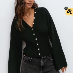 Gina tricot fitted waist cardigan - Snygg svart kofta med v-ringning och pärlemorknappar hela vägen framtill. Modellen har långa, vida ärmar och ribbad midja som ger en smickrande passform. Perfekt att styla med jeans för en trendig look. Helt ny, lappen kvar! HELT SLUTSÅLD PÅ HEMSIDAN!