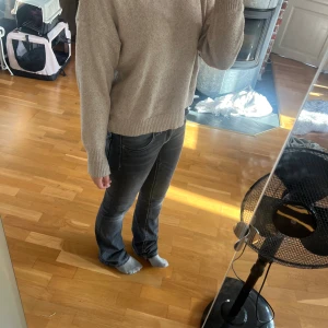 Beige stickad tröja med rund hals - Säljer en beige stickad tröja med rund hals och långa ärmar. Tröjan har ribbade muddar vid ärmslut och nederkant, vilket ger en schysst och enkel look. Perfekt för dig som gillar neutrala färger och vill ha något mjukt och skönt att dra på sig.