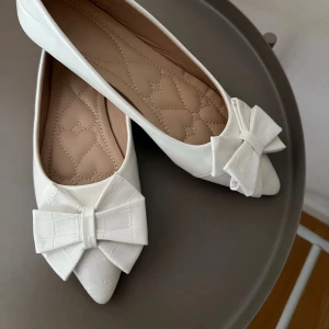 Vita ballerinaskor  - Jättefina vita ballerinaskor med rosetter. Säljer pga att de ej passade mig. Dom är strl 38 men skulle säga att de passar strl 39. Jättefint skick och aldrig använda. Köpta utomlands💕