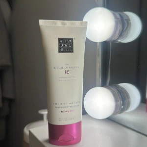 Rituals The Ritual of Sakura hand balm - Rituals The Ritual of Sakura recovery hand balm i en vit tub med rosa lock. Perfekt för torr hud och har en lyxig känsla med doft av körsbärsblom. Tuben rymmer 70 ml och är smidig att ha med i väskan. Använd nära gånger men mer än halva kvar. Luktar så gott.