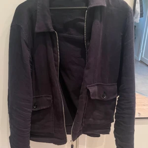 Mörkblå overshirt med dragkedja - Säljer nu en snygg mörkblå overshirt från zara som är i väldigt bra skick. Overshirten har två fickor framtill som är väldigt bra som man kan stänga med hjälp av en knapp. Jackan är även väldigt varm inuti så den är perfekt för lite kyligare och blåsigare dagar.