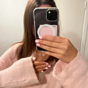 Ljusrosa omlottkofta med knytband - Supermjuk ljusrosa omlottkofta med breda ärmar och knytband i sidan. Koftan är stickad och har en avslappnad passform som ger en mysig vibe. Perfekt att slänga på sig över ett linne eller t-shirt för en chill look.