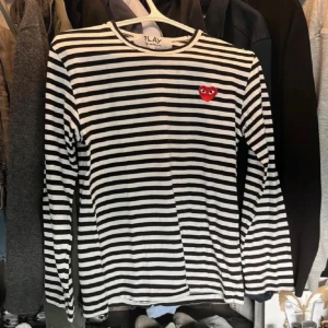 Randig långärmad tröja Comme des Garçons - Säljer en svartvit randig långärmad tröja från Comme des Garçons Play. Tröjan har ett ikoniskt rött hjärta med ögon broderat på bröstet och är tillverkad i mjuk bomull. Perfekt för dig som gillar stilrena och trendiga plagg. Storlek S men sitter som XS