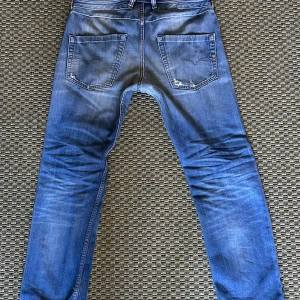 Diesel jeans - Säljer ett par blå Diesel Belther jeans med snygga slitningar och trasiga detaljer på benen. Jeansen har klassisk femficksdesign, normal passform och är tillverkade i jeansmaterial. Perfekta för dig som gillar en avslappnad och trendig look.
