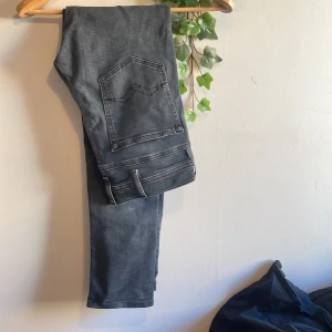 Replay Blue Jeans i mörkblå denim - Säljer ett par Replay Blue Jeans i mörkblå tvättad denim med klassiska femficksdetaljer och snygga kontrastsömmar. Byxorna har Replay-logga på bakfickan och läderpatch i midjan. Perfekta för dig som gillar stilrena jeans med en modern touch.