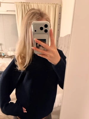 Mörkblå stickad tröja - Mysig mörkblå stickad tröja med rund hals och långa ärmar. Perfekt för kyliga dagar och enkel att matcha med olika outfits. Tröjan har en klassisk passform och ribbade muddar vid ärmslut och nederkant.