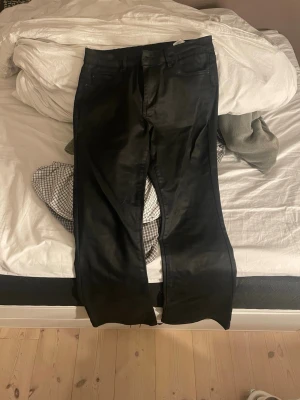 Svarta jeansbyxor från Vero Moda - Säljer ett par svarta jeansbyxor med skinimitation från Vero Moda med och normal passform. Boutcut modell 