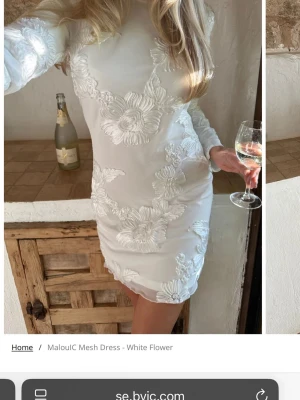 Vit blommig klänning från BYIC - Superfin vit kortklänning från BYIC med stora blommiga broderier. Klänningen har lång ärm, rund hals och figurnära passform. Perfekt för dig som vill sticka ut med en elegant och unik look. Kommer inte använda då jag fick fel storlek, men helt oanvänd ☺️